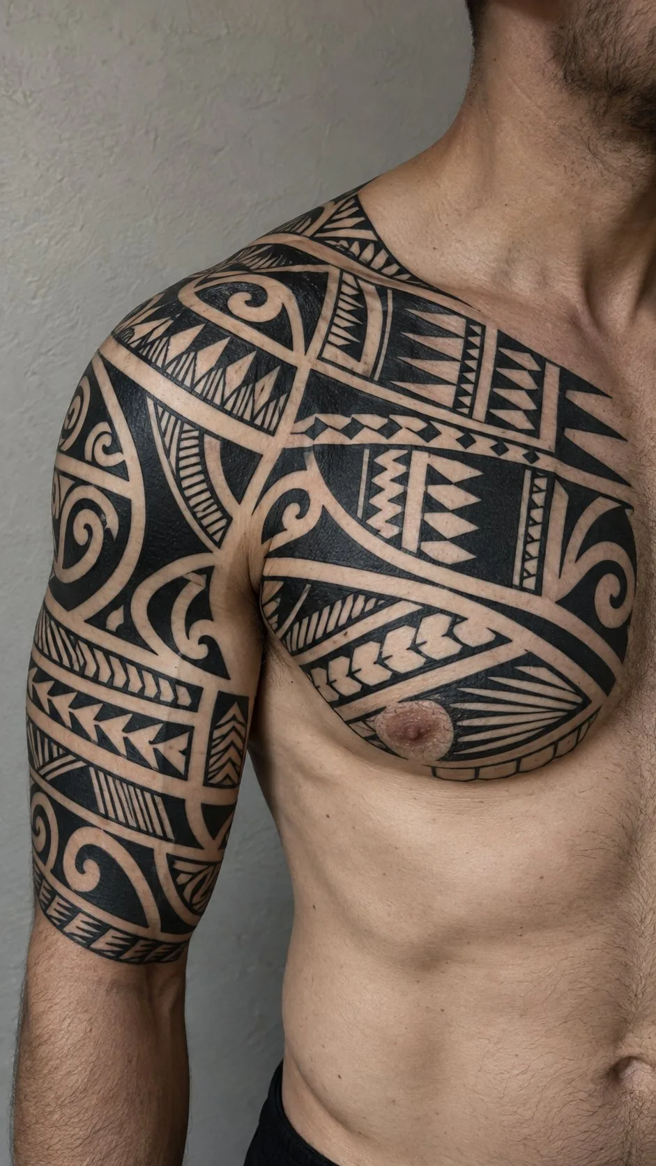 Polynesian-style blackwork chest and shoulder tattoo