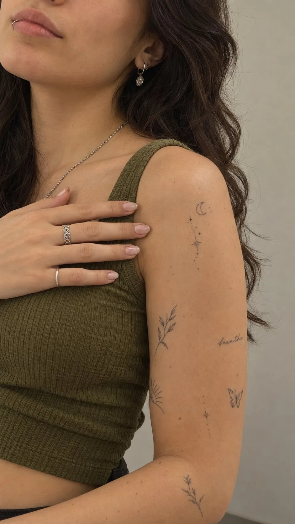 Small fine-line tattoos scattered on the upper arm