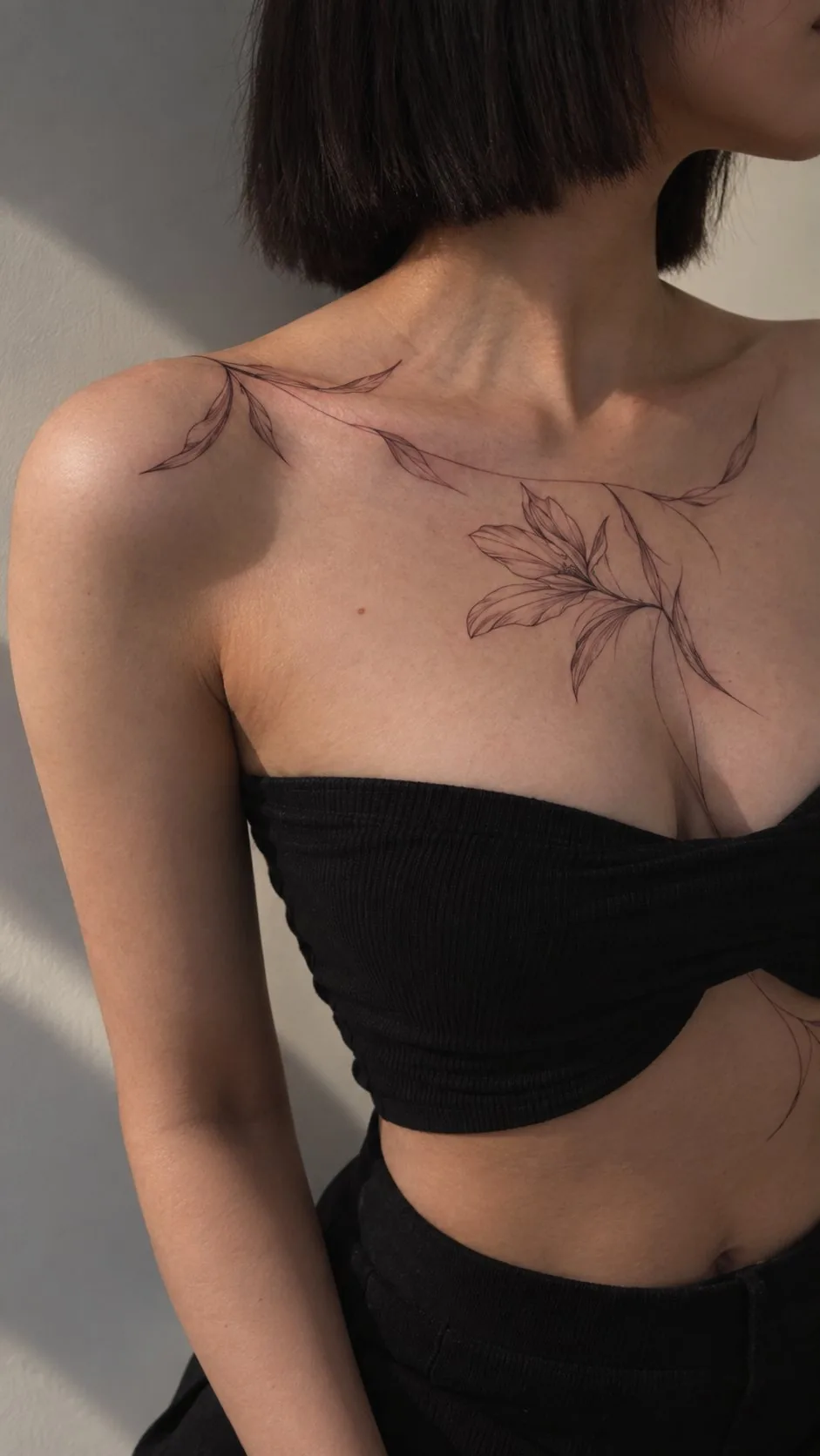 Fine-line floral tattoo across the collarbone